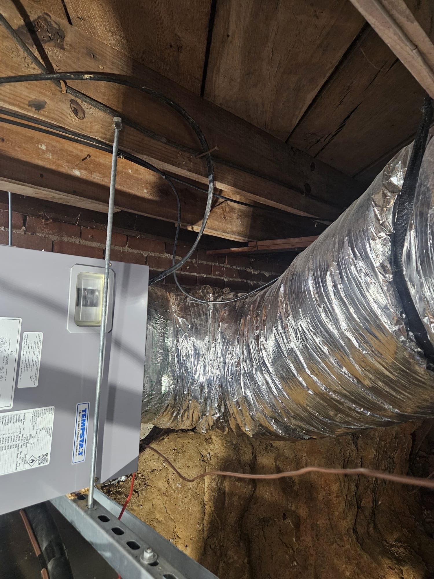 Neatly installed air ducts and system components in a crawl space, reflecting high installation standards