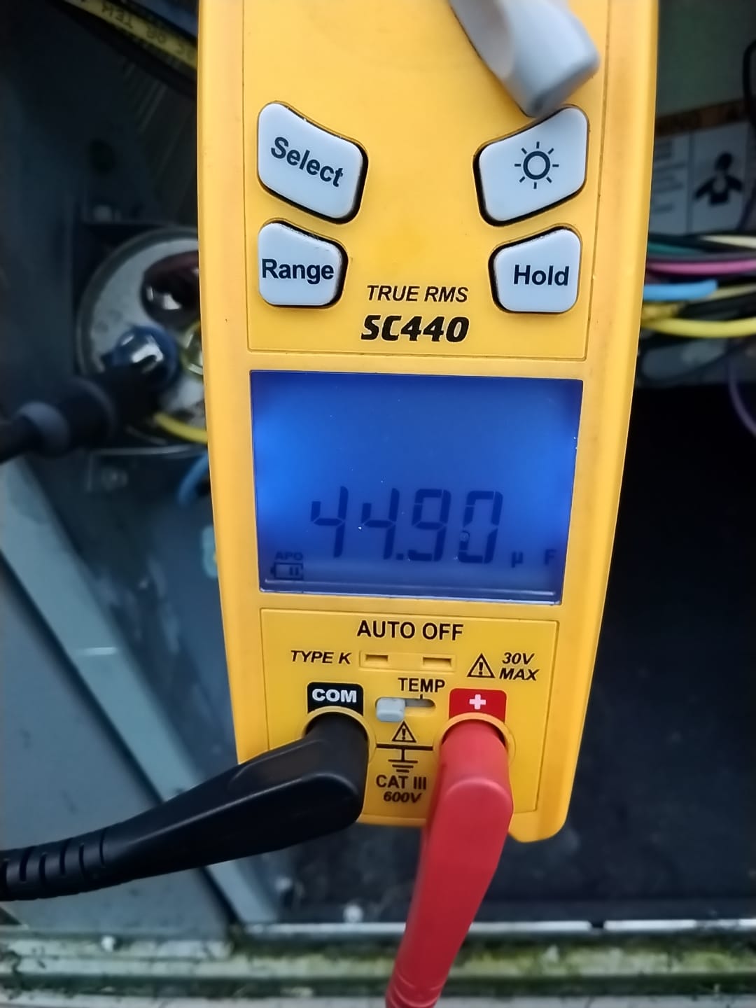 Technician measuring capacitor performance with a multimeter