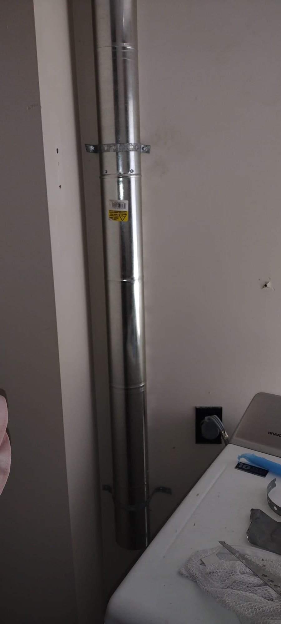 Shiny new galvanized vent piping secured to the wall