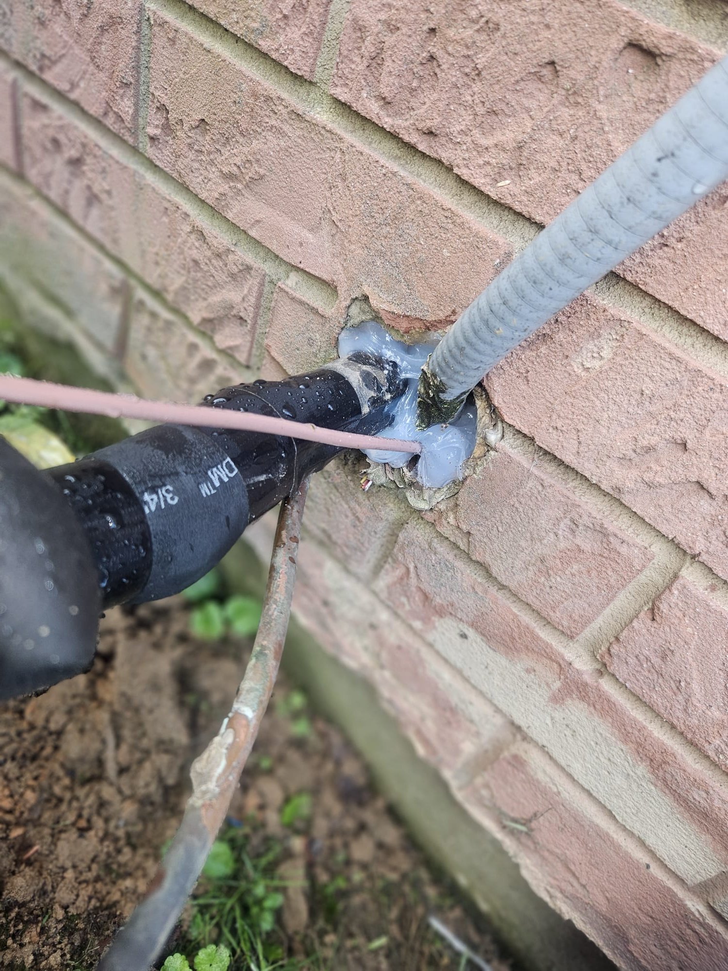 Refrigerant line entry sealed against brick wall