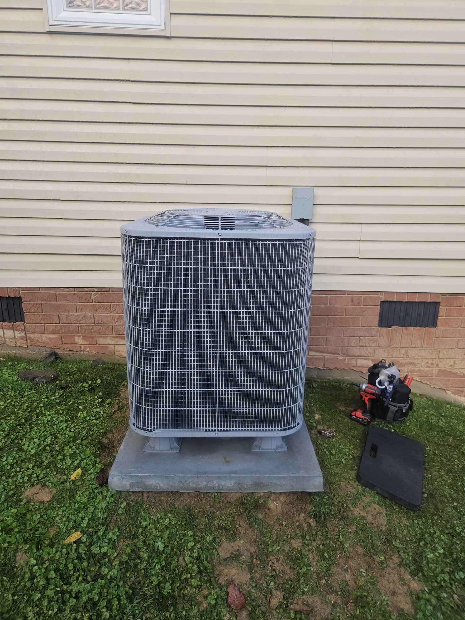 Outdoor unit on a sturdy pad with technician’s tools nearby