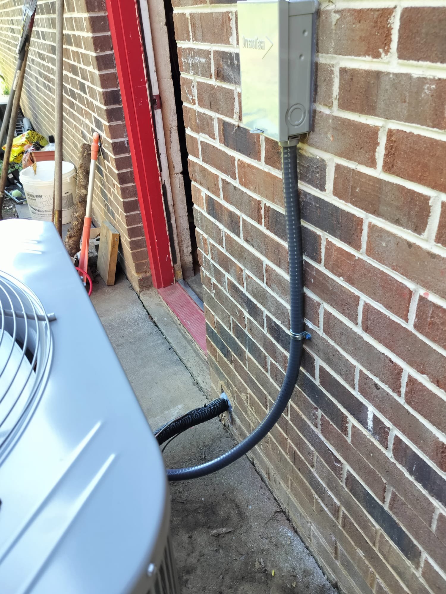 Exterior view showing the outdoor unit, insulated line set, and disconnect box