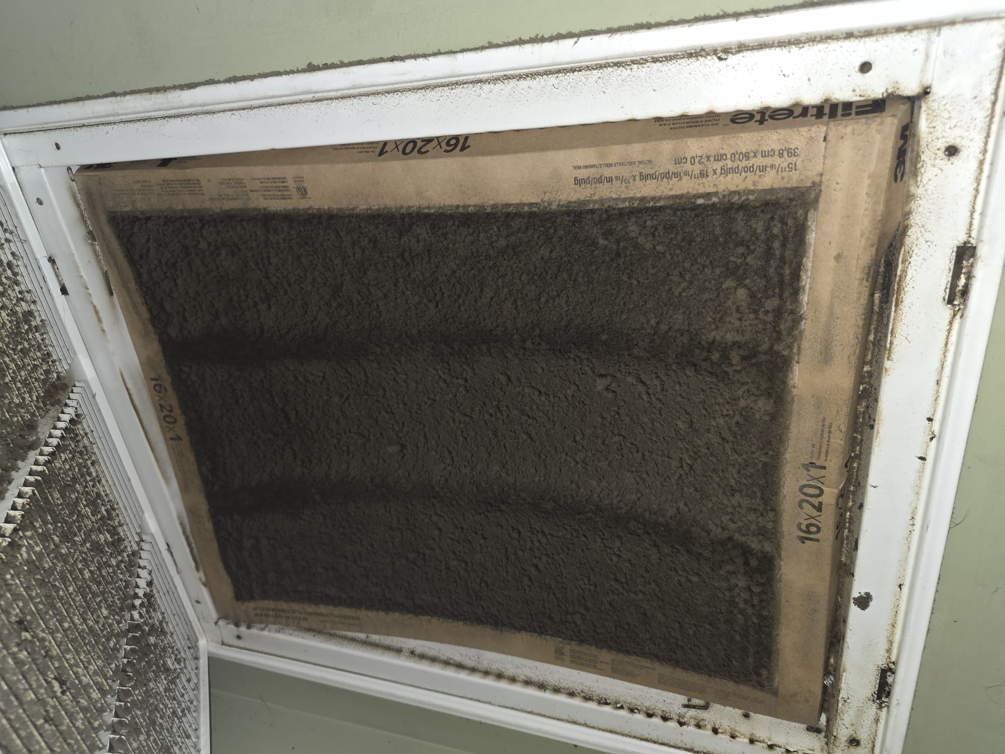 Dirty HVAC filter clogged with dust and debris, limiting airflow in a ceiling vent.