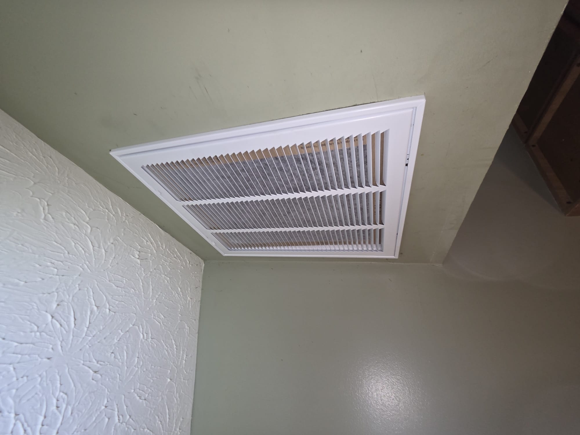 Clean, newly installed wall-mounted HVAC return air grille.