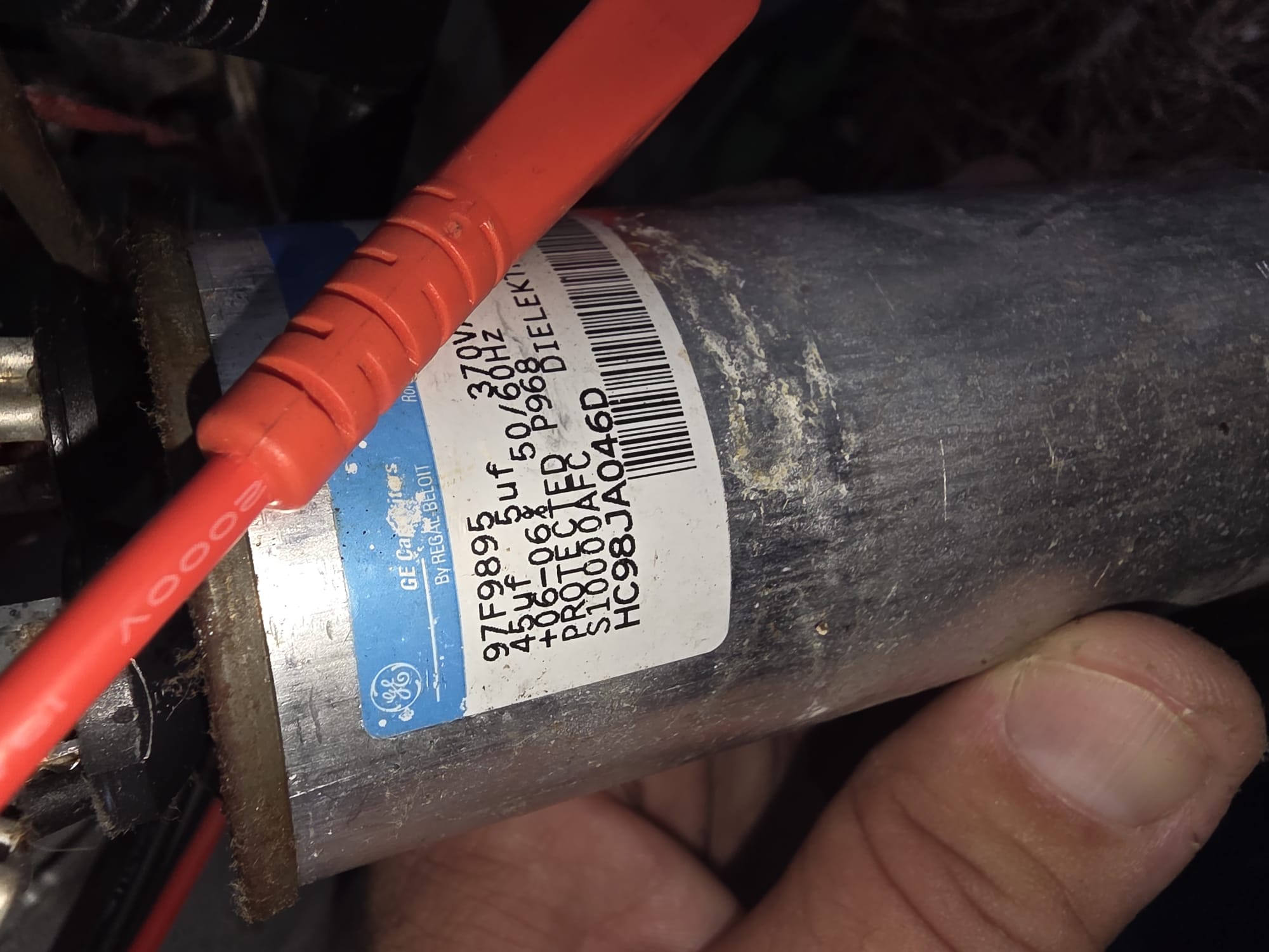 Technician testing a dual run capacitor using a meter
