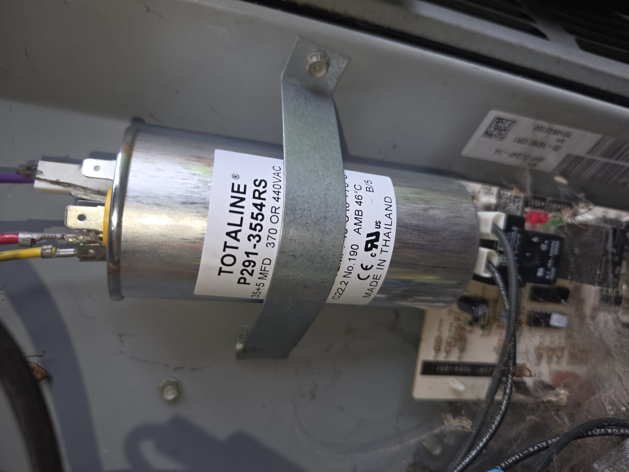 A newly installed replacement capacitor inside an outdoor unit
