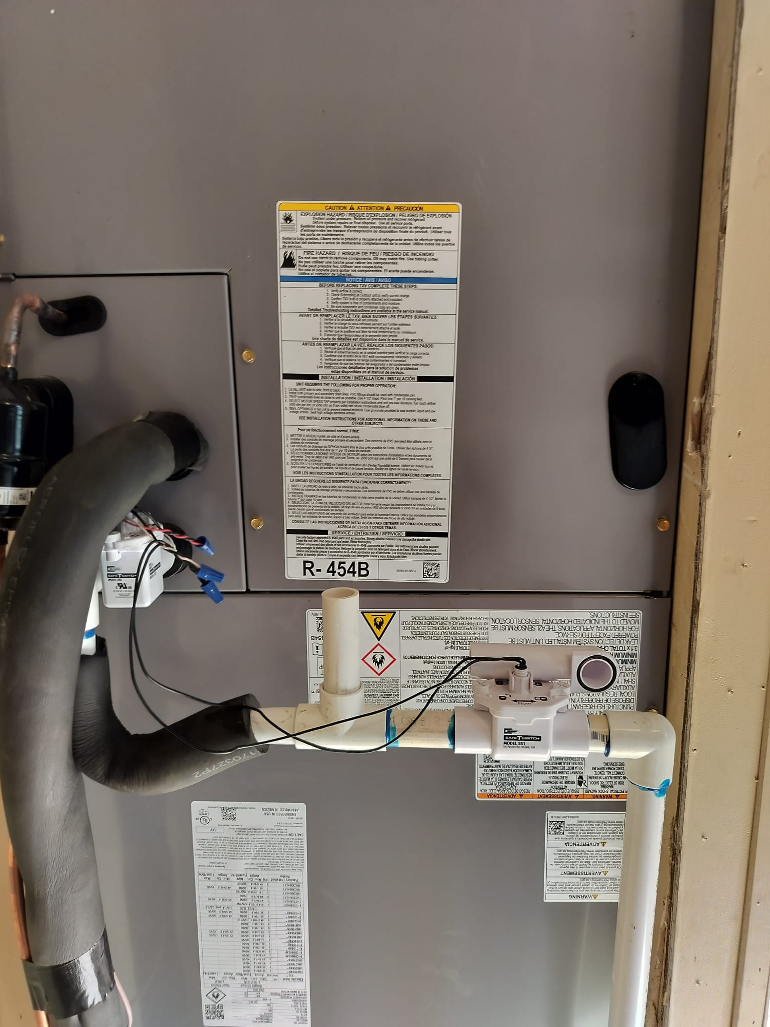 New indoor HVAC air handler installed in a closet with clean drain piping and safety protection