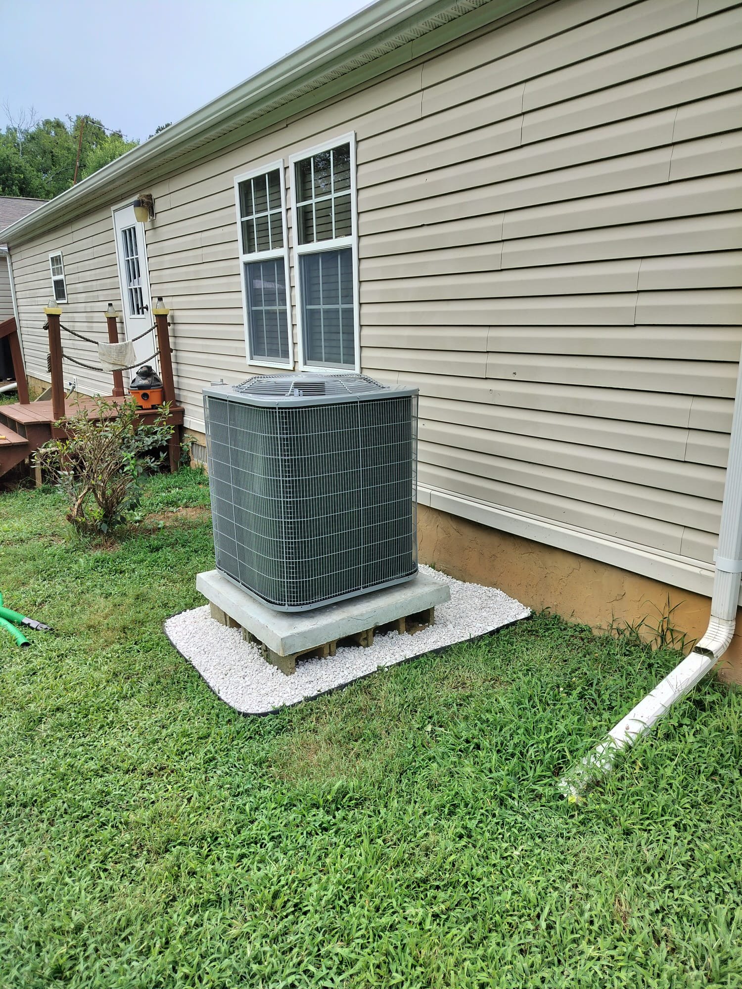 New outdoor heat pump condenser installed on a clean pad beside the home
